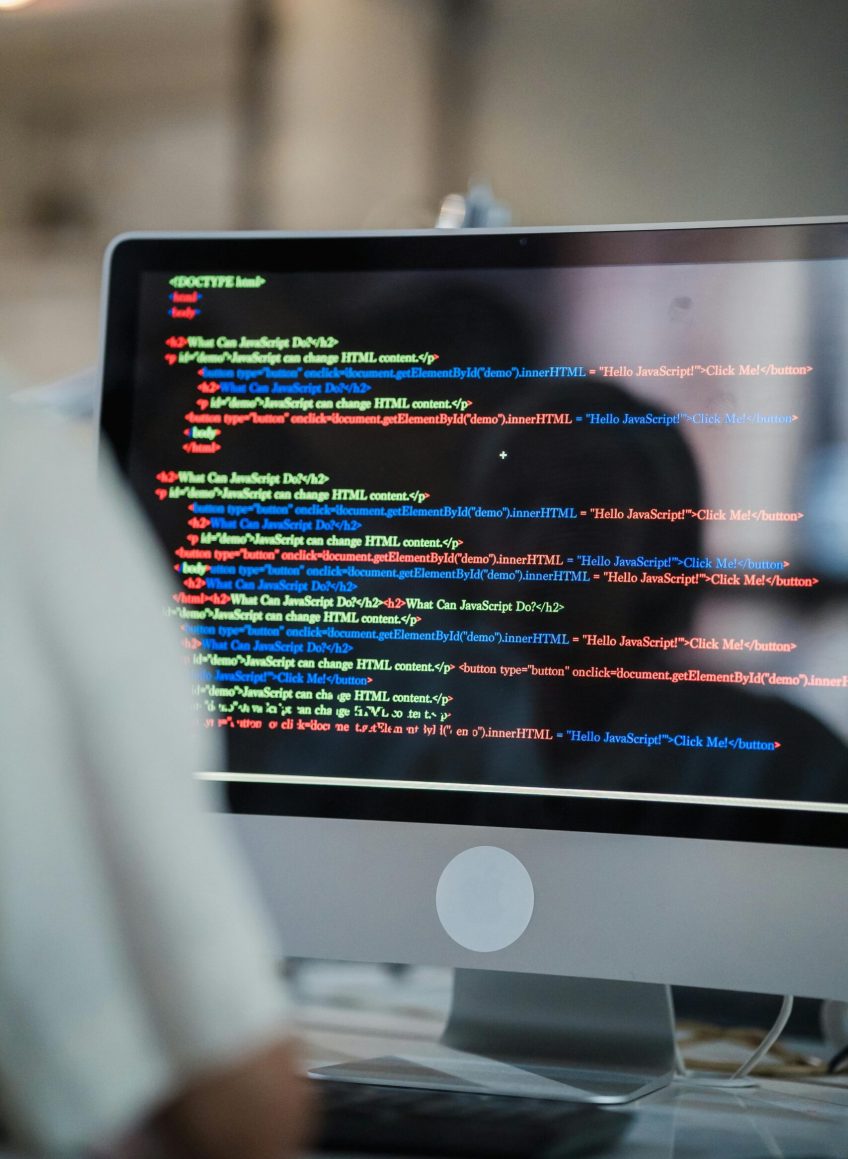 A close-up of a computer screen displaying colorful coding script in an office environment.